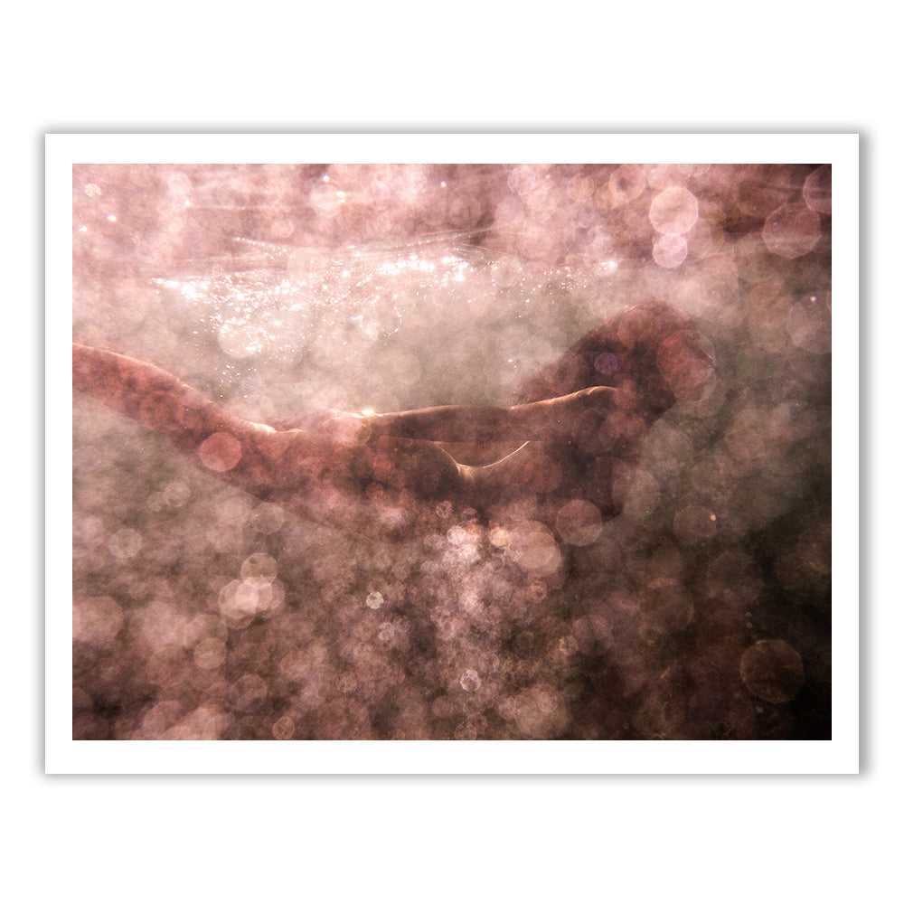 A person swimming underwater, encompassed by a dreamy haze of light and bubbles. The scene is illuminated by Blush 02 from Francesca Owen, imbuing the surroundings with a warm, ethereal glow that creates a magical, almost abstract effect—as if captured on fine art paper using archival pigments.