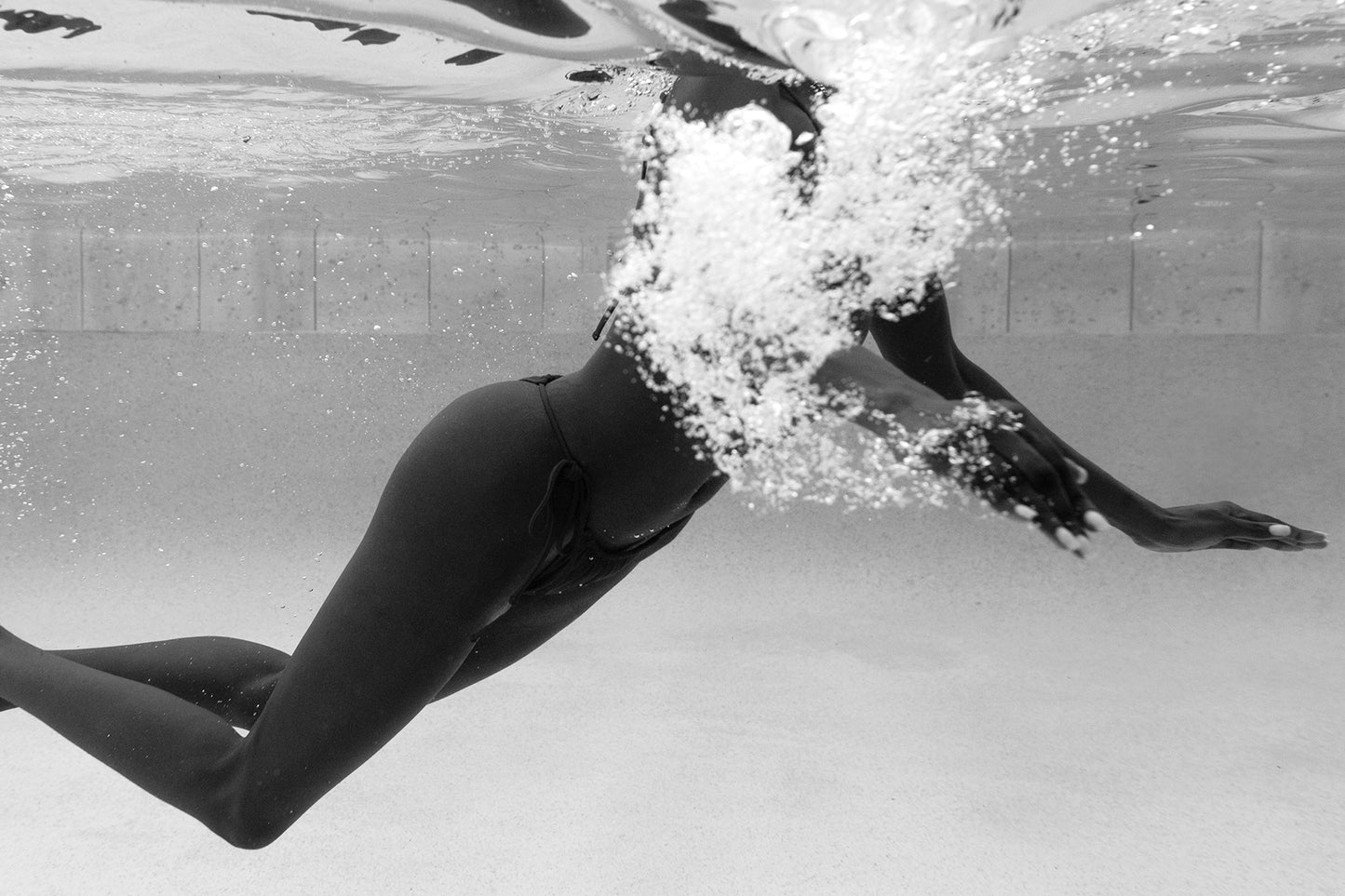 Elegance #5" by Francesca Owen is a black and white underwater photo of a swimmer on fine art paper, showcasing fluid motion with bubbles above. The custom-made piece captures elegance in a pool setting and is hand-signed for authenticity.