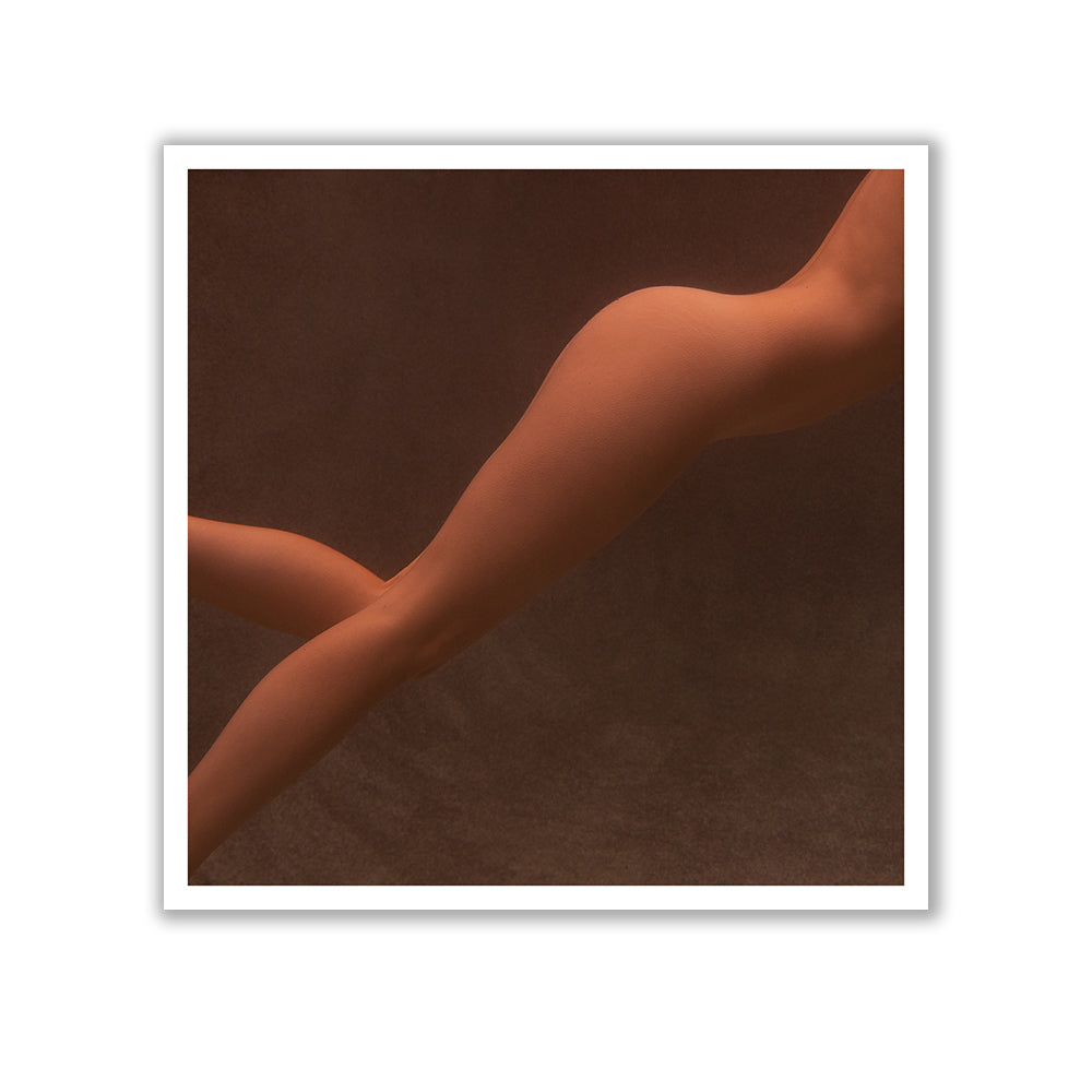 A photograph featuring a close-up of a nude human body, showcasing the legs and lower torso against a dark background. The skin tone is warm, and the image is artistically composed with smooth lines and shadows. Available as fine art prints, Reflect no.4 by Francesca Owen is crafted with archival pigments and comes with a certificate of authenticity.
