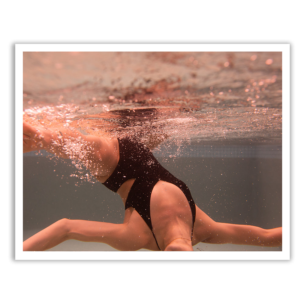 Self Reflection 14," an artistic underwater photograph by Francesca Owen, captures a person swimming mid-movement in a black swimsuit. The water is slightly murky, with bubbles and splashes surrounding them. This sepia-toned image, printed on fine art paper using archival pigments, evokes a warm and nostalgic effect.