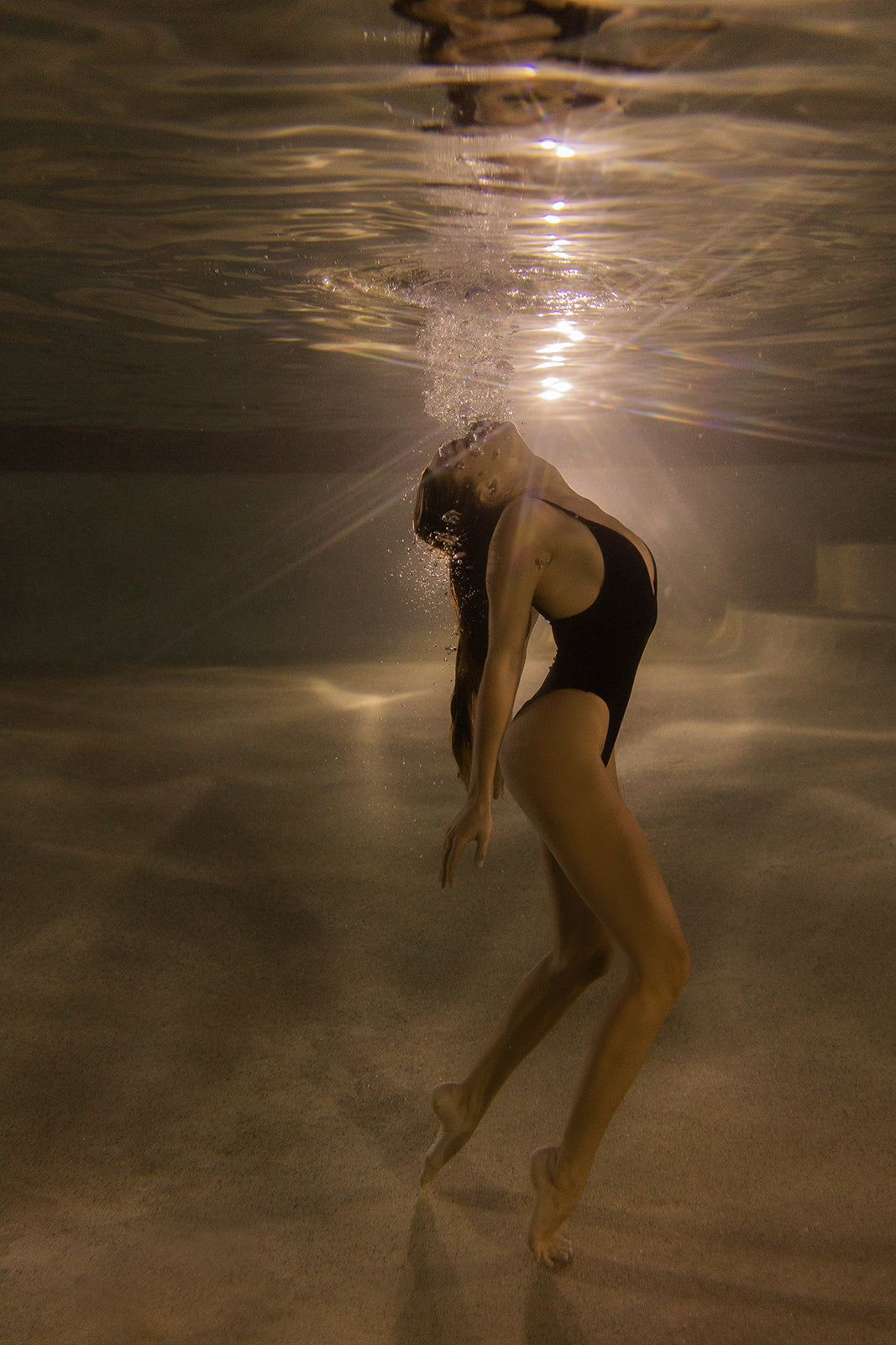 A woman in a black swimsuit arches underwater, sunlight illuminating her as bubbles rise. "The Bower #5" by Francesca Owen is available as hand-signed art prints on fine art paper with a certificate of authenticity.