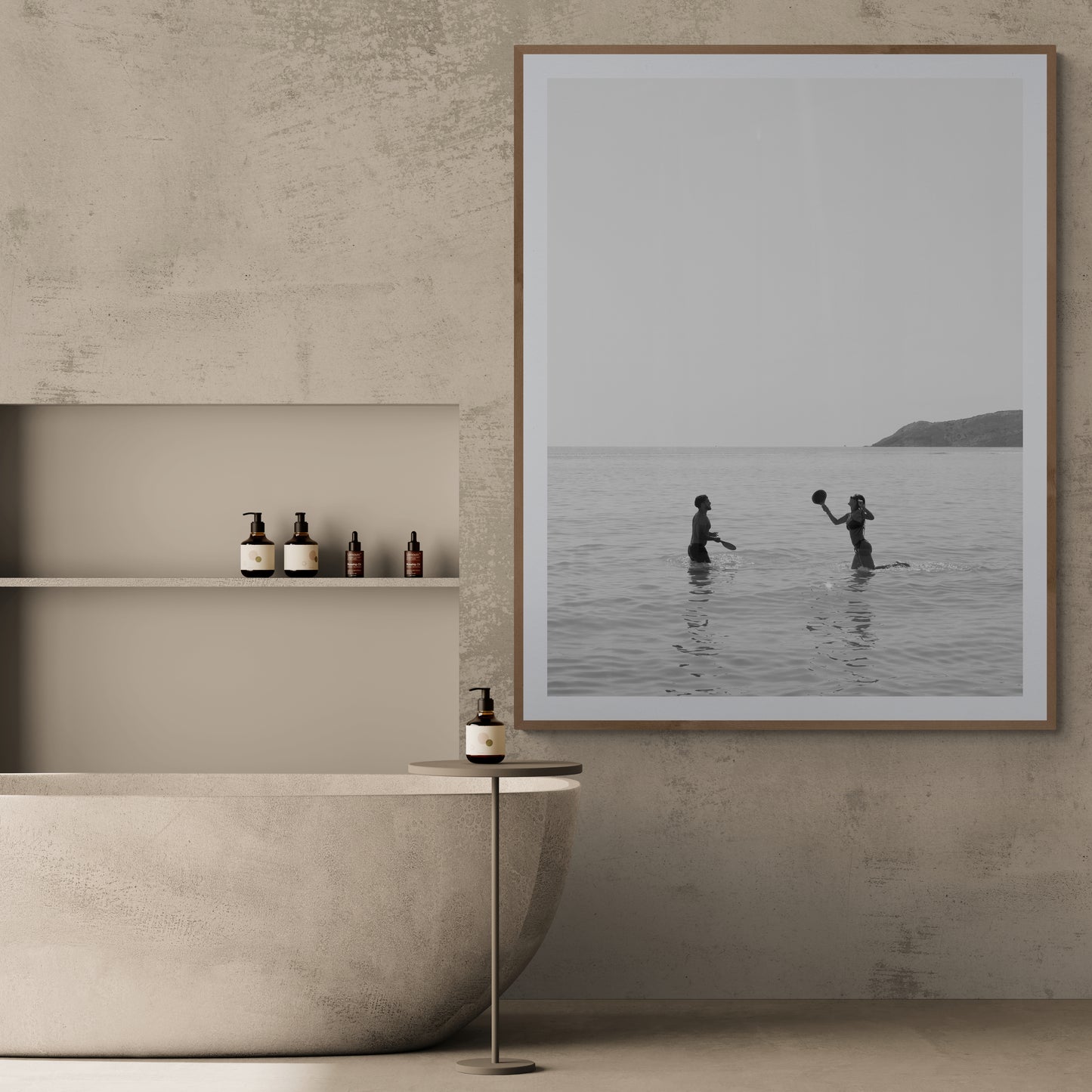 In the minimalist bathroom, a freestanding tub is complemented by a small table holding a bottle and shelves stocked with toiletries. Adding elegance to the textured wall is "Magic in Milos #8," a large framed photo by Francesca Owen, printed on fine art paper using archival pigments, capturing two people playing in the sea.