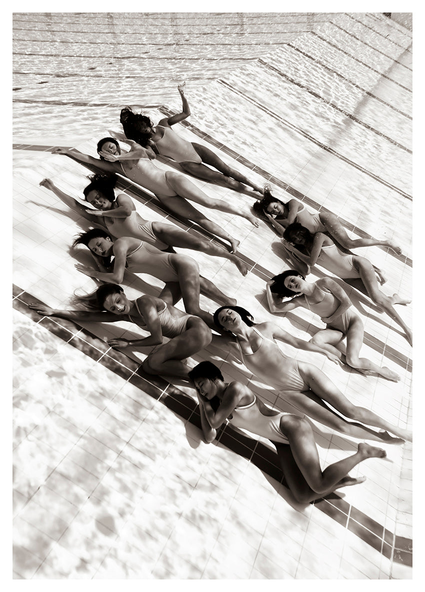 Ladies in Waiting #2, by fine art photographer Francesca Owen, presents a striking black and white image of eleven people in swimsuits lying on their sides in a staggered formation. Their positioning creates a unique, artistic pattern in the shallow pool. This limited edition print on giclee fine art paper emphasizes the geometric lines of the pool floor.