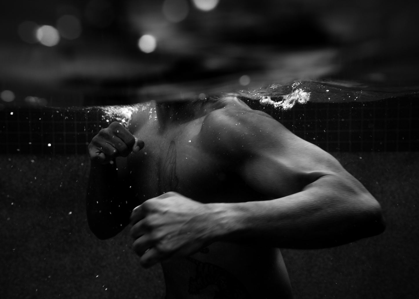 New Waters #1" by Francesca Owen features a dramatic black and white photograph of a shirtless man partially submerged in water, with the waterline at his chest. His fists are clenched and raised as if shadowboxing underwater, creating dynamic bubbles and ripples that stand out under the striking lighting. This captivating piece, hand signed on fine art paper, powerfully captures raw emotion.