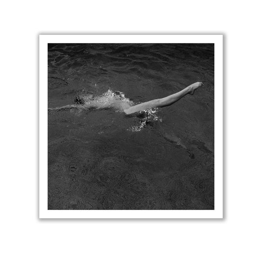 The black and white image titled "Liquid Legs #1" by Francesca Owen captures a swimmer mid-stroke, with only their right arm and part of their torso visible above the water's surface. Printed on fine art paper with archival pigments, this piece ensures rich detail and longevity, and comes with a certificate of authenticity.