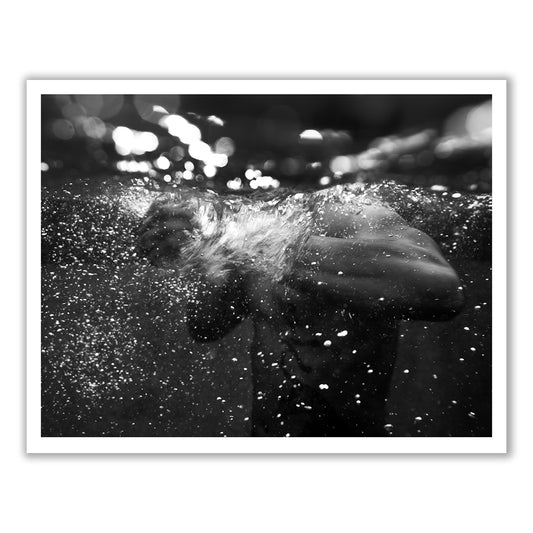 Introducing **New Waters #4** by **Francesca Owen**, a stunning black and white fine art photograph capturing a person underwater, surrounded by bubbles and light reflections. The visible arms through the water add dynamic movement and contrast against the dark background. Enhanced with archival pigments, this artwork shines when custom framed.