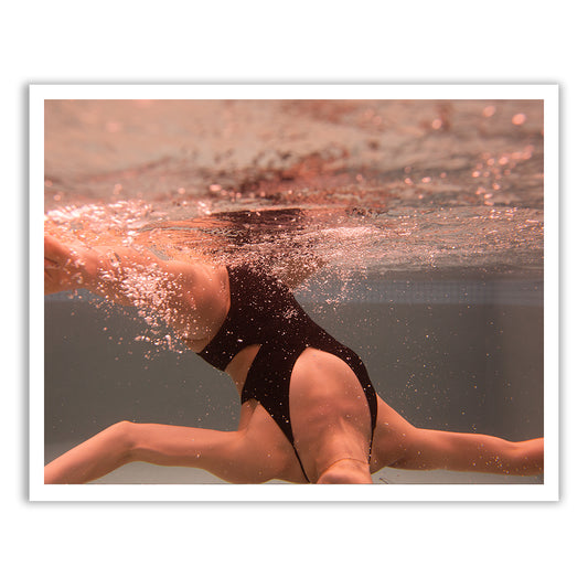 Self Reflection 14," an artistic underwater photograph by Francesca Owen, captures a person swimming mid-movement in a black swimsuit. The water is slightly murky, with bubbles and splashes surrounding them. This sepia-toned image, printed on fine art paper using archival pigments, evokes a warm and nostalgic effect.