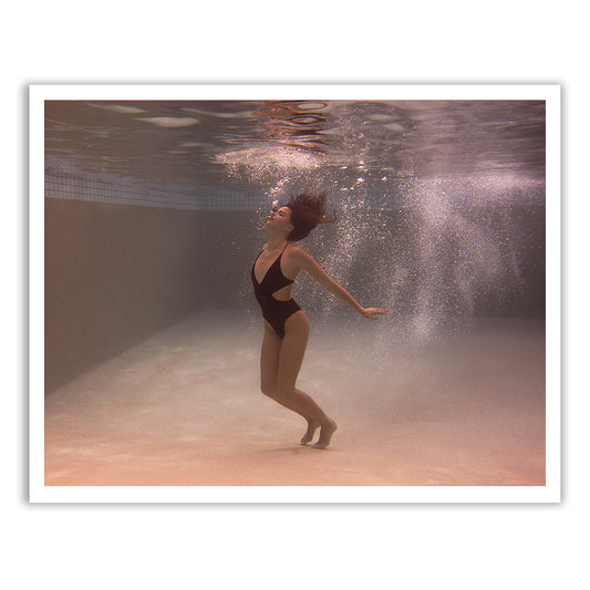 A mesmerizing underwater photo titled "Self Reflection 03" by Francesca Owen features a person in a black swimsuit gracefully posing with arms extended and hair flowing. Bubbles surround them, conveying a sense of rising or floating in a serene indoor pool setting. This exquisite image is captured beautifully for fine art paper using archival pigments, and it comes with a certificate of authenticity.