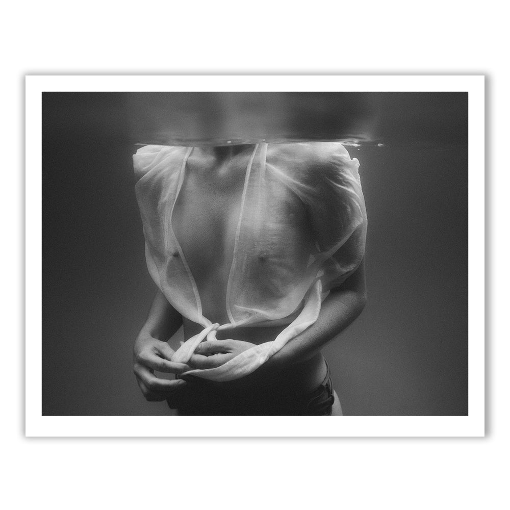 Black and white photograph titled "Softness #2" by Francesca Owen, featuring a partially submerged person wearing a sheer, wet shirt. The upper part of the body from the shoulders to the waist is visible, with the head above water and out of the frame. The person is holding the edges of the shirt. Printed on fine art paper using archival pigments for lasting quality.