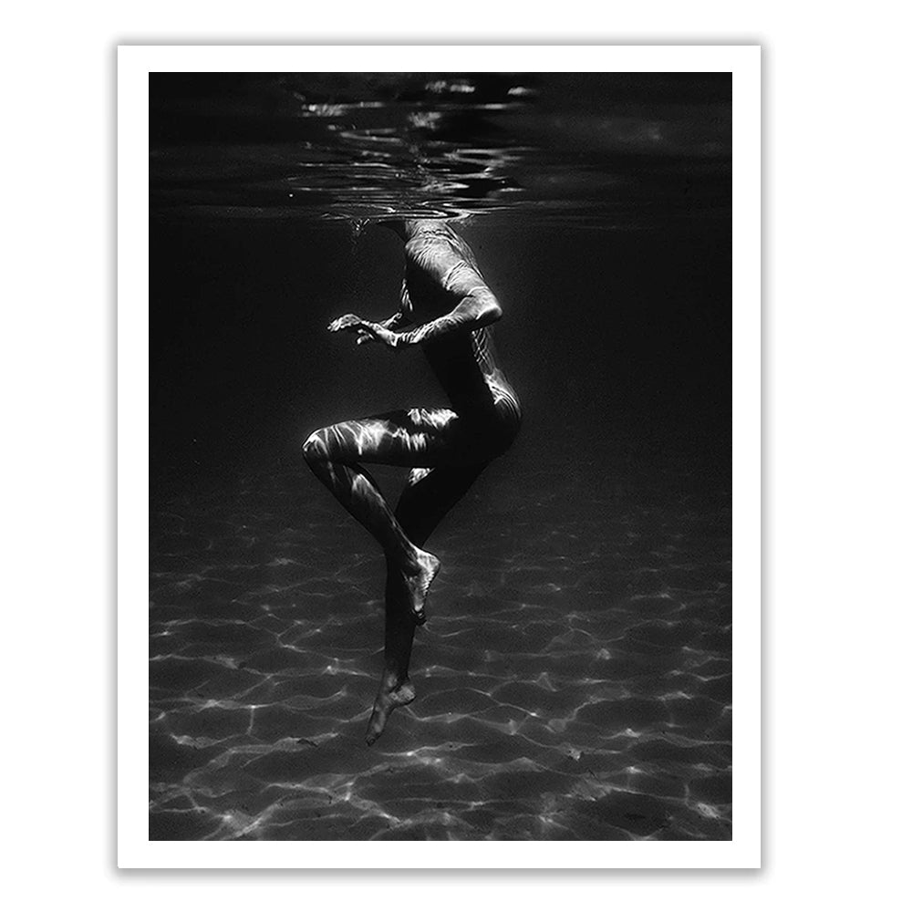 Still Waters #1 by Francesca Owen is a black and white photograph capturing a person underwater, appearing to float gracefully in an upright position with gently bent arms and legs. Light reflections create intricate patterns on their body and the surrounding water. This stunning piece is printed using archival pigments on fine art paper, with worldwide shipping available.
