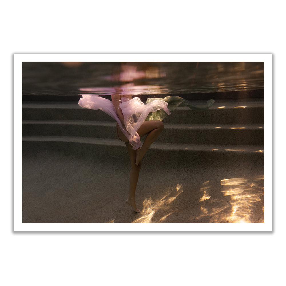 A person underwater, partly visible in flowing translucent fabric, with one leg raised and sunlight patterning the pool evokes dreamy fine art in "Sunset #3" by Francesca Owen.