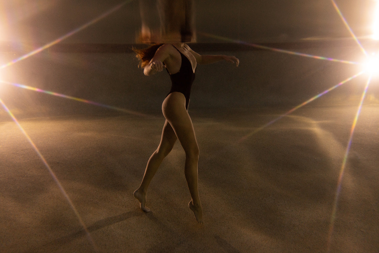 A person in a black swimsuit poses underwater with arms extended and one leg lifted, surrounded by soft light—creating a dreamy atmosphere in "The Bower #3," a fine art print by Francesca Owen.