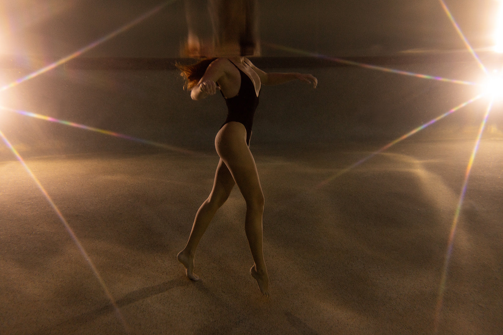 A person in a black swimsuit poses underwater with arms extended and one leg lifted, surrounded by soft light—creating a dreamy atmosphere in "The Bower #3," a fine art print by Francesca Owen.