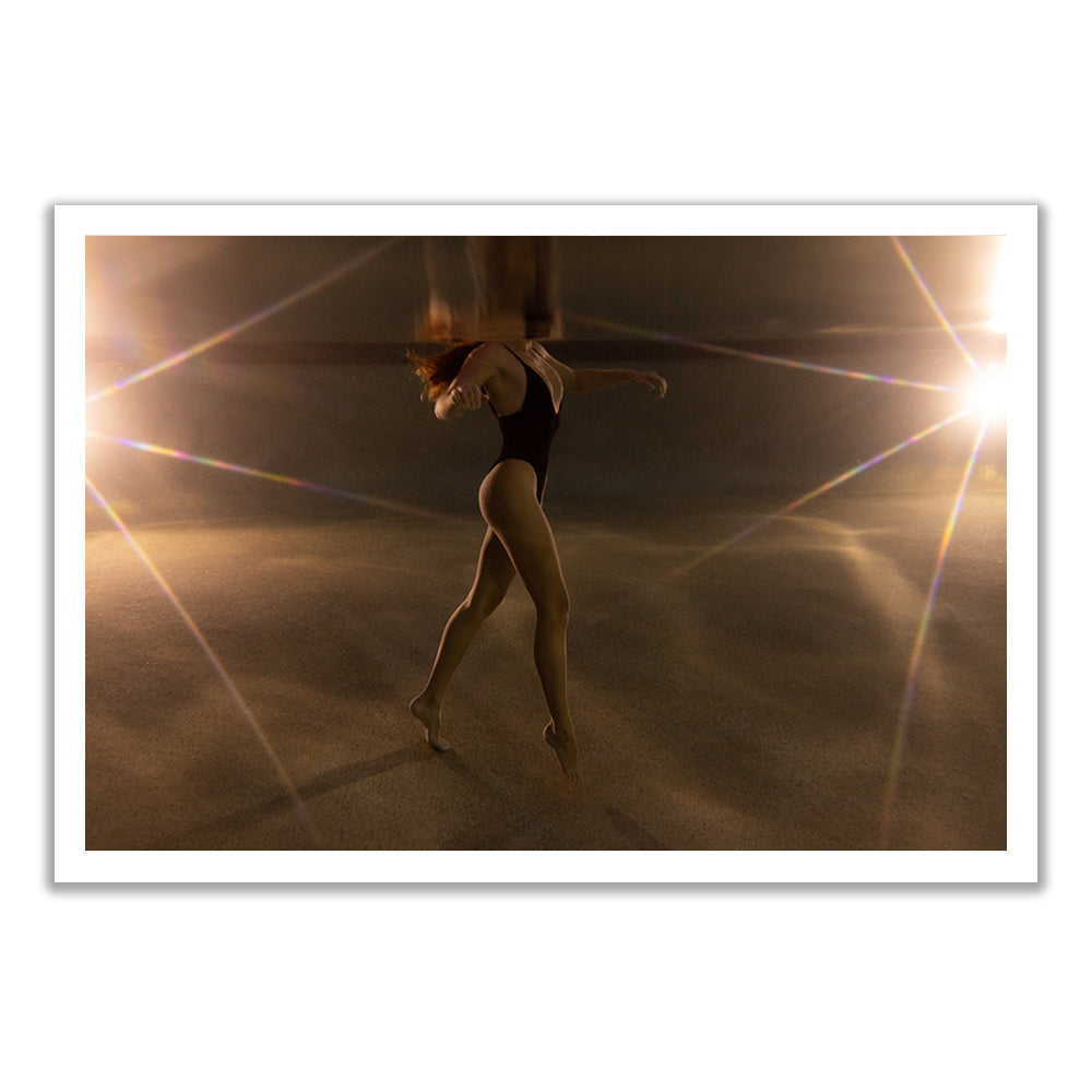 A dancer in a black leotard moves gracefully in a dimly lit space with starburst lights and reflections. "The Bower #3" fine art print by Francesca Owen includes a certificate of authenticity.