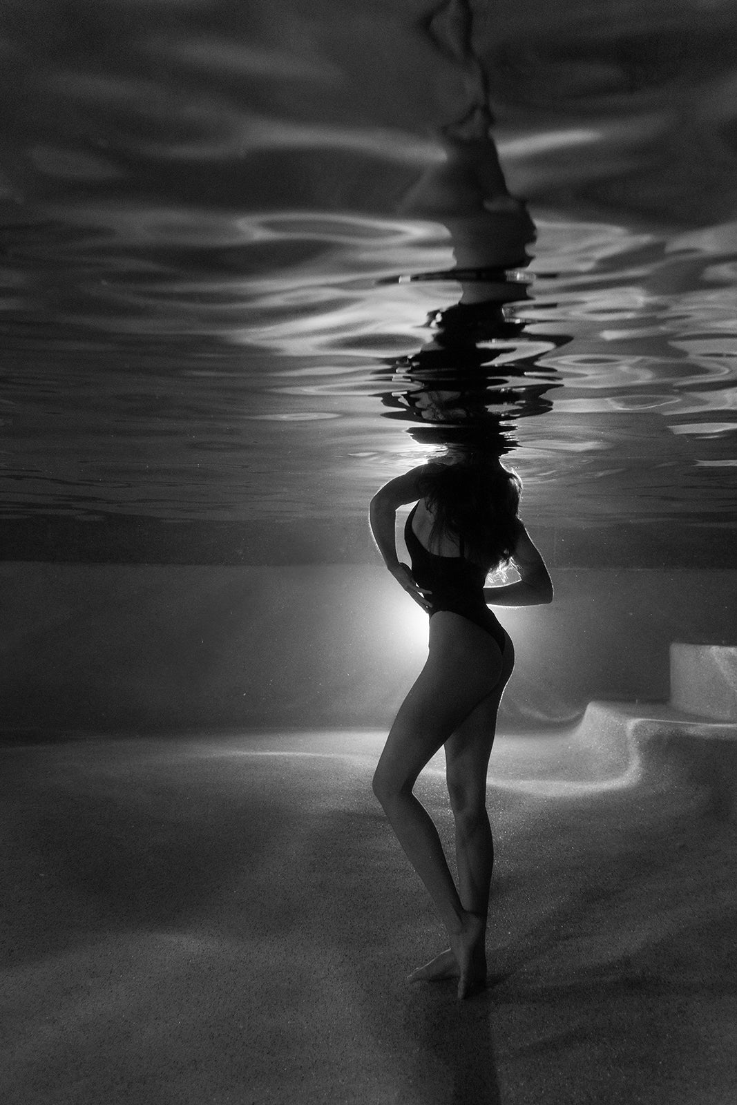 The Bower #6 by Francesca Owen features a silhouetted swimmer underwater, illuminated against bright light with rippling reflections. This black and white hand-signed art print comes with a certificate of authenticity.
