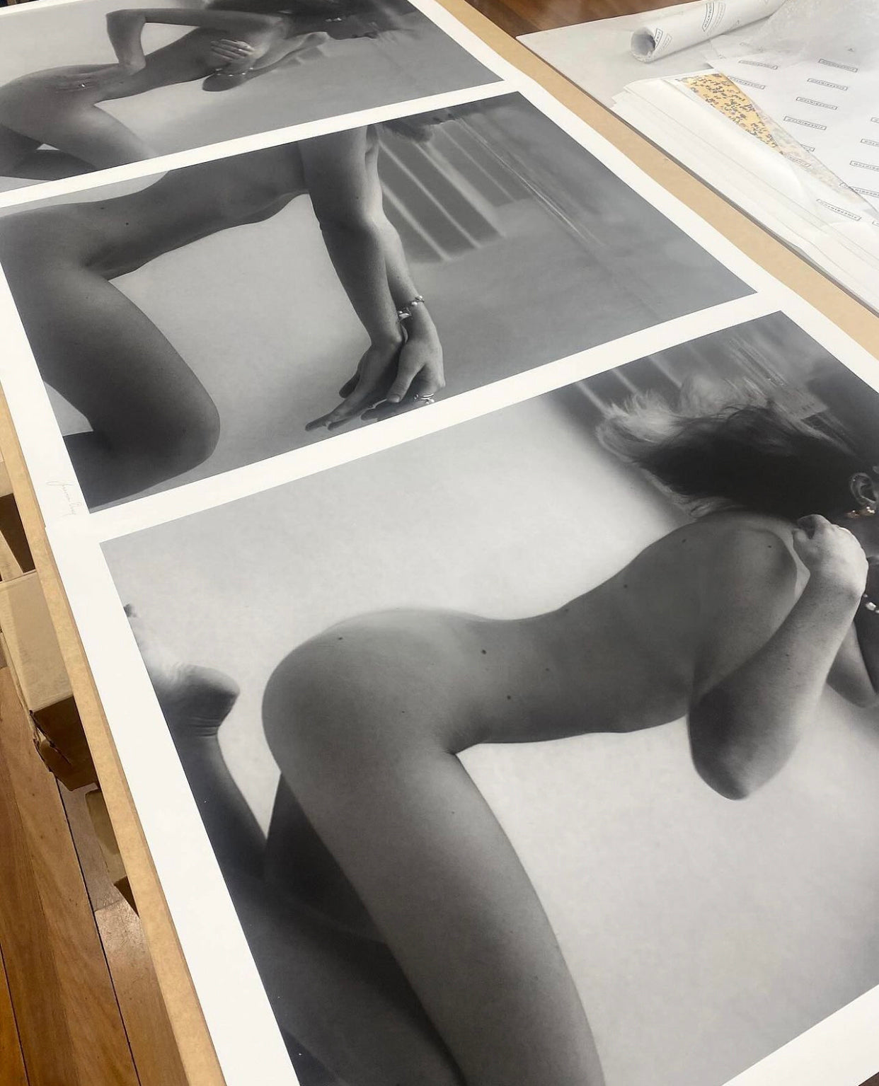 UNVEILED captures a serene black and white photograph by Francesca Owen, featuring a person underwater in a pool. The individual is kneeling with their head tilted back, hair floating, and reflections on the water surface creating a mirrored effect. Adorned with visible gold earrings and bracelet, this limited edition piece is printed on fine art paper using archival pigments.