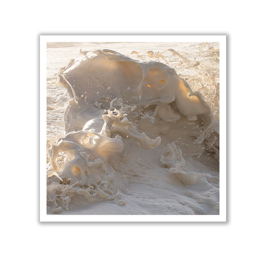A close-up photograph from the "Wild Seas Part I, V I — Limited Edition Print" by Francesca Owen captures a foamy ocean wave in motion, with sunlight illuminating the frothing water to create an artistic and dynamic natural scene. This exclusive art piece is elegantly framed in white and crafted as an archival pigment print to ensure lasting beauty.