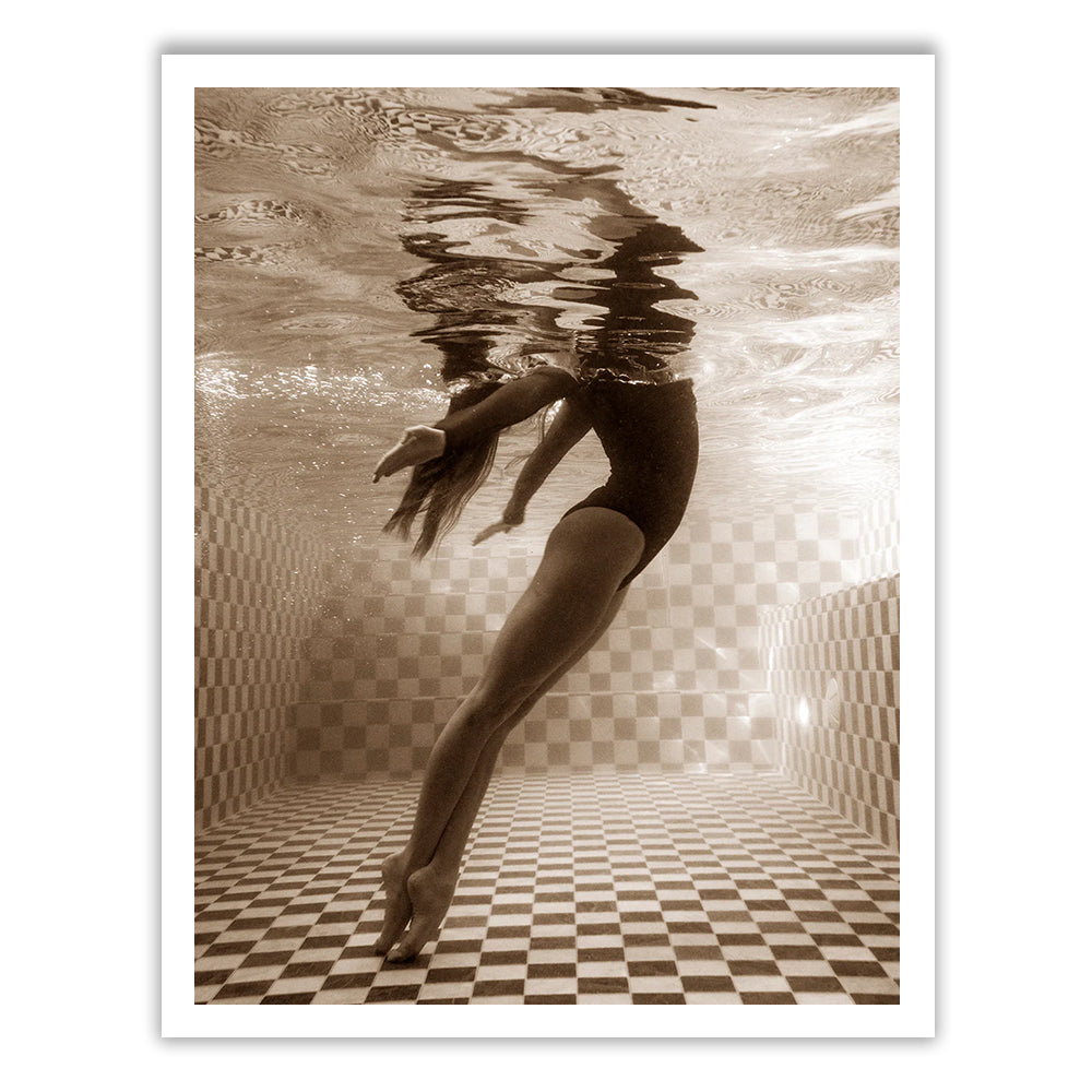 Wild at Heart no.2" by Francesca Owen is a sepia-toned photo of a person underwater in a swimming pool, framed with a white border. The person is in a streamlined position, with arms extended and toes pointed, swimming near the tiled pool floor and surface. The water creates rippling reflections above. This piece is available as fine art prints using archival pigments, each one hand signed by the artist.