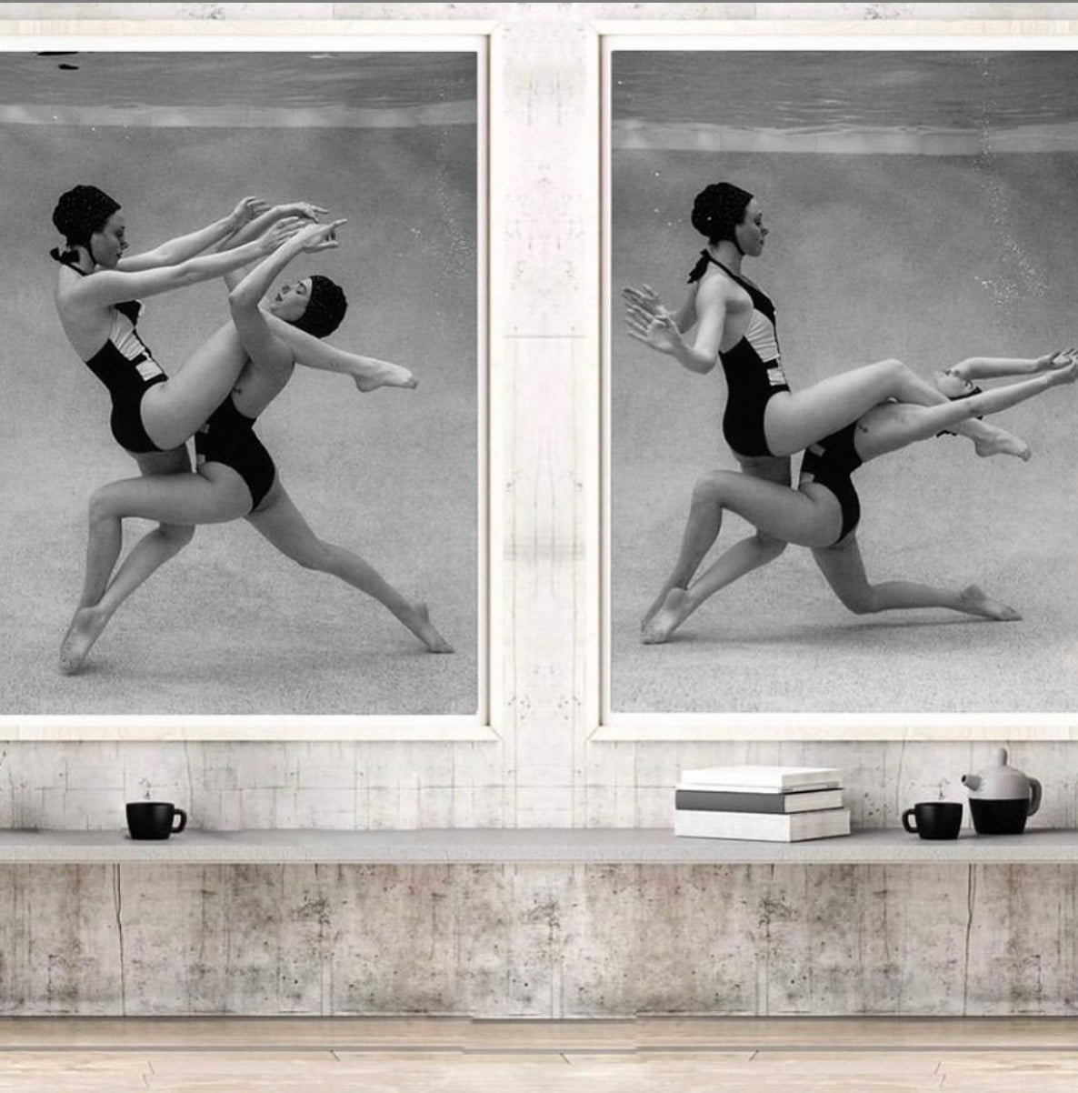 Two synchronized swimmers perform an underwater routine in black and white. One balances on the other's raised knee, extending her arms and legs gracefully. Both wear matching swimsuits and swim caps as air bubbles rise from their movements. Perfect for custom framing, this scene, titled "Palm Springs Duo #2" by Francesca Owen, is a timeless art print.
